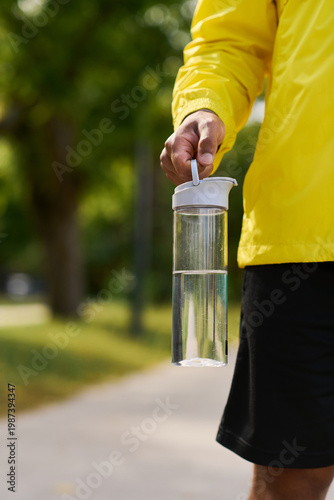 Foto Young man in yellow windbreaker enjoys outdoor workout on a sunny spring day