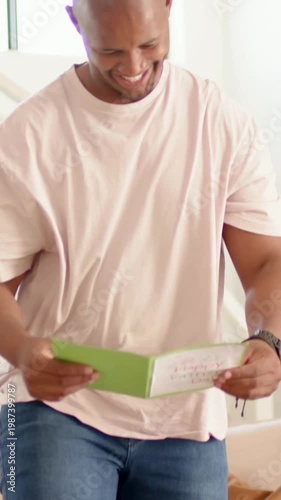 Vertical video: Opening green Fathers Day card dad in pink tee reading placing it on table at home