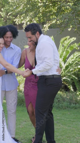 Linking hands after ceremony, bride in white gown and groom dancing to celebrate on garden lawn