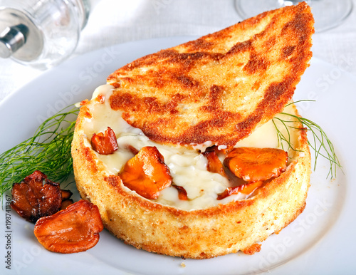 Fried camembert stuffed chanterelles on white plate.