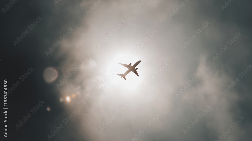 Naklejka premium Airplane flying overhead, creating a silhouette against sun rays breaking through clouds, symbolizing exploration and adventure