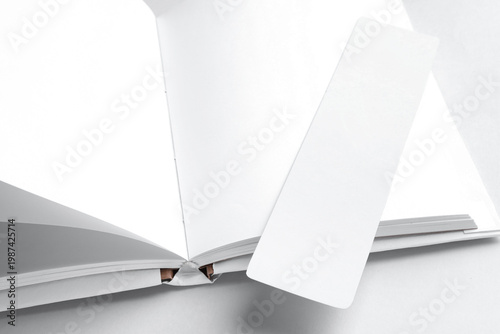 Book with white bookmark on light grey background, closeup. Space for text