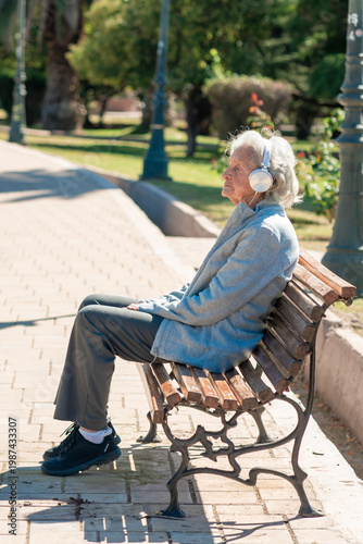 An 85-year-old grandmother enjoys a peaceful moment listening to music in the park