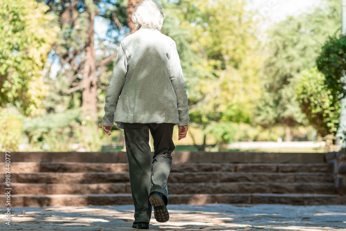 Fotografie An 85 year old grandmother walks up stone steps in a park with her daughter