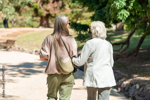 An 85 year old grandmother and her daughter enjoy a peaceful walk together in the park