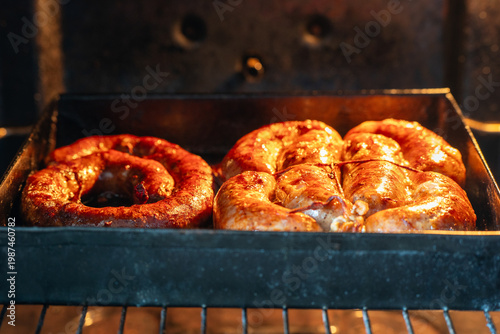Homemade sausage baked in the oven on a baking sheet, hot meat dish close-up