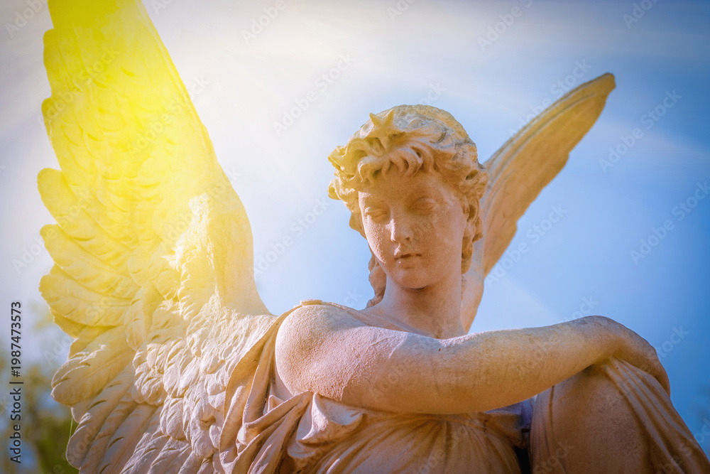 Fototapeta premium Angel statue in warm sunlight, spiritual concept of remembrance, peace and eternity.