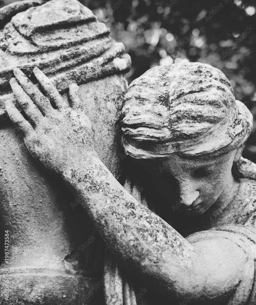 Fototapeta premium Mourning angel statue embracing urn, symbol of grief, loss and remembrance.