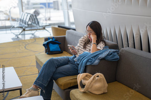 Young Woman Relaxing in Airport Lounge, Using Smartphone While Waiting for Flight