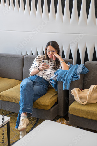Young Woman Relaxing on Couch While Using Smartphone in Modern Lounge Setting