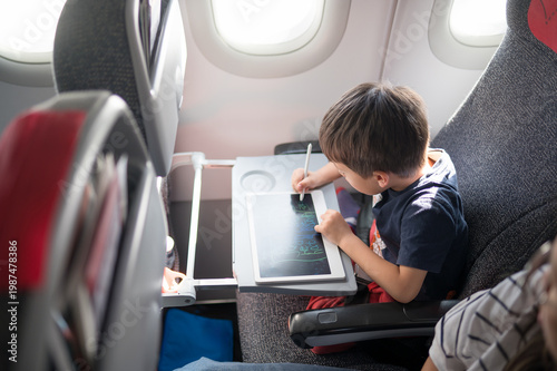 Young Boy Engaged in Creative Drawing on Tablet While Traveling in Airplane