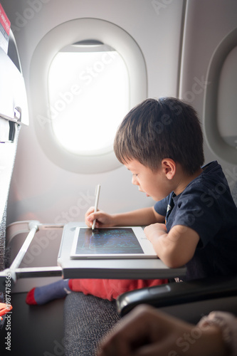 5 Year Old Boy Engaged in Creative Drawing on a Tablet While Traveling in an Airplane