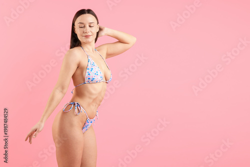 Obraz na plátně Beautiful woman in stylish swimsuit posing on pink background