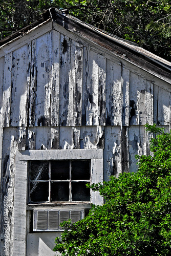 Old derilict house with peeling paint and 1950’s era window air conditioning unit