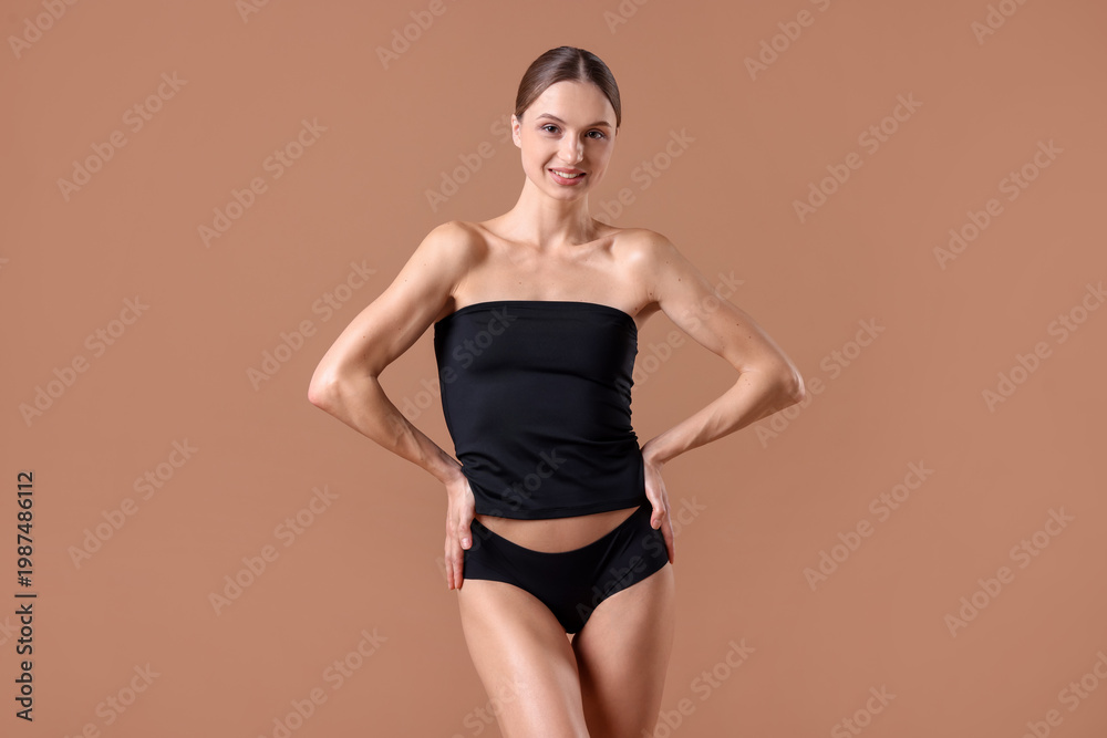 Obraz premium Smiling woman in underwear with slim body on beige background