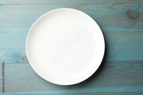 One empty plate on light blue wooden table, top view