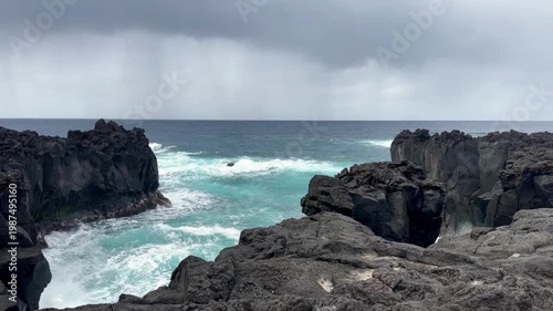 Rugged volcanic coastline in azores portugal with turquoise ocean waves under dramatic cloudy sky scenic seascape