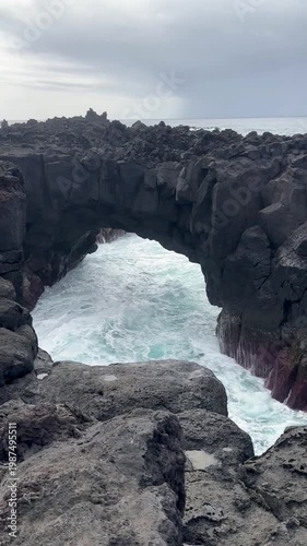Natural rock arch over ocean waves in azores portugal with rugged volcanic cliffs and dramatic seascape