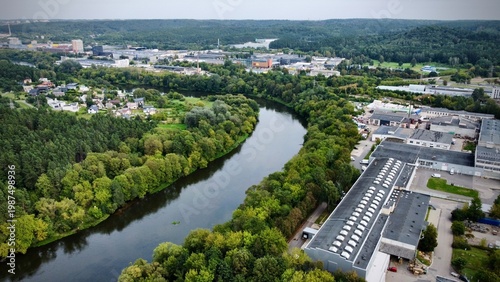 Tableau sur toile Aerial view showcases Vilnius Industrial Zone in Lithuania, featuring a mix of industrial buildings with grey rooftops adjacent to a winding river lined with dense green foliage