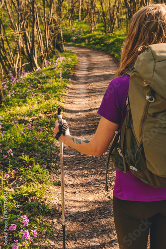Female Hiker with Backpack and Trekking Poles Walking in Forest
