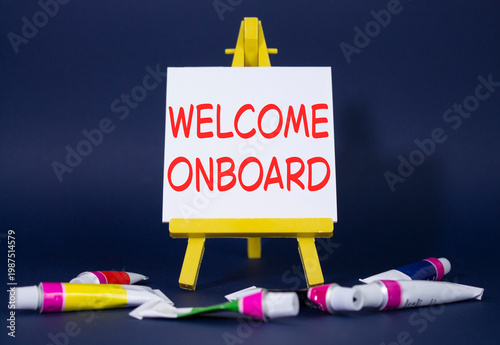 Welcome onboard symbol. Concept words Welcome onboard on wooden blocks. Beautiful deep blue background with paints and easel. Business and Welcome onboard concept. Copy space.