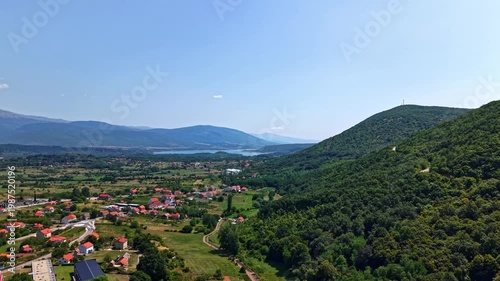 Aerial view of the scenic valley near Vrlika and Lake Peruca in the Dalmatian hinterland, Croatia, featuring red-roofed houses and lush green mountains