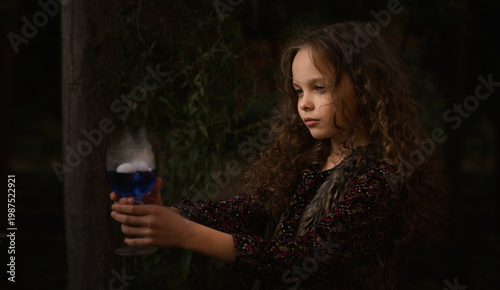 Schilderij op canvas Happy Halloween Concept! Cute little with green witch's potion with smoke in the decorated garden