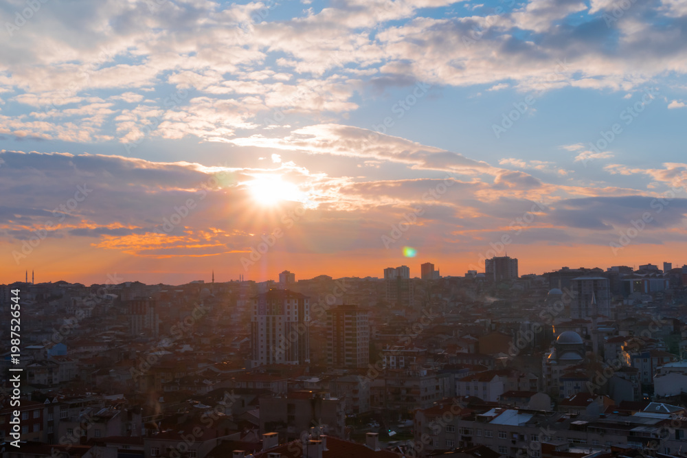 Fototapeta premium Delightful sunset sky with the setting sun and clouds over the city of Istanbul, Turkey in the evening - apartment, residential buildings silhouettes. Cloudscape, cityscape and architecture concept