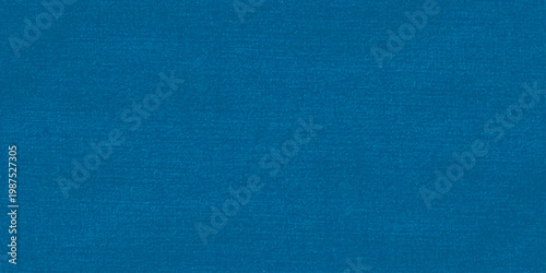 A dark vintage denim material with a rough blue canvas texture and grunge cotton fabric pattern creates a blank textured textile background for an artistic paper wallpaper surface