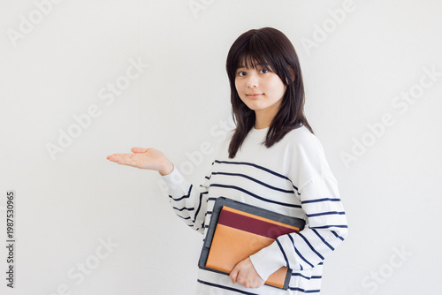 資料を持って案内する若い女性・ビジネスと教育イメージ（コピースペースあり）