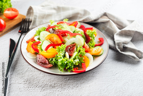 vegetable salad of fresh tomatoes, cucumbers, onions, lettuce on white plate.