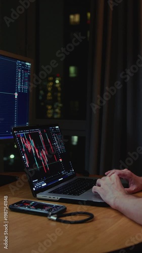 Man in trader home office. Monitor and laptop are on table. Trading program or exchange. Male analyzes candlestick charts for crypto market. Managing Investment portfolio, monitoring financial data