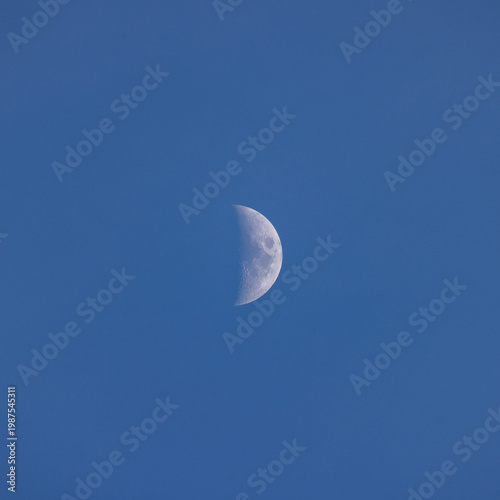 Crescent moon shines bright against clear blue sky