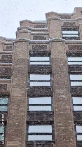 Snow falling over New York city streets with historic architecture, winter atmosphere, cold weather, seasonal snowfall, atmospheric cityscape