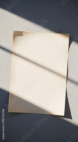 Blank cream paper sheet mockup on textured gray concrete surface with dramatic sunlight window shadows. Minimalist aesthetic template for poster, flyer, or art print branding