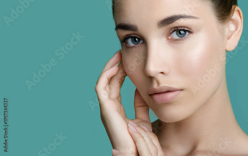 Beautiful young women with perfect fresh skin and makeup touches her face. Portrait of model with make-up, eyebrows  and long eyelashes. Beauty and Spa, skincare and wellness. Selective focus.