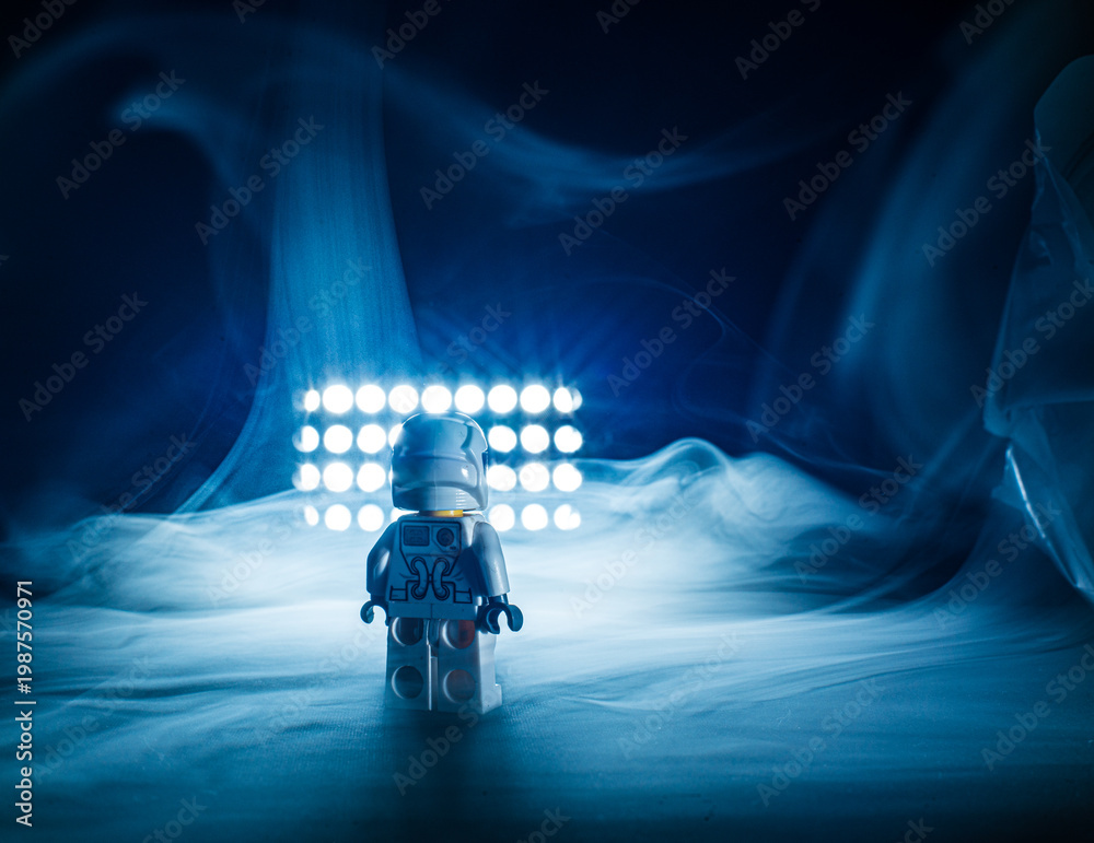 Fototapeta premium Toy astronaut standing alone in dramatic smoky light.