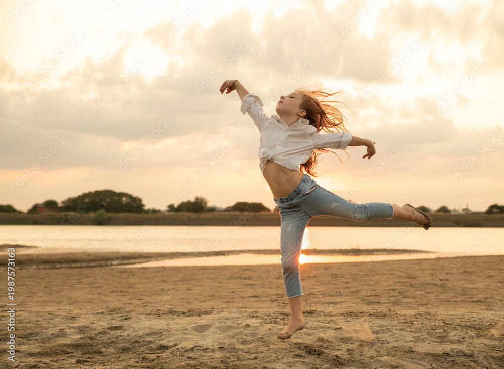custom made wallpaper toronto digitalBeautiful little girl jumps on the sand on the river bank. Little ballerina girl is dancing on the nature. Kid and child on vacation. Selective focus