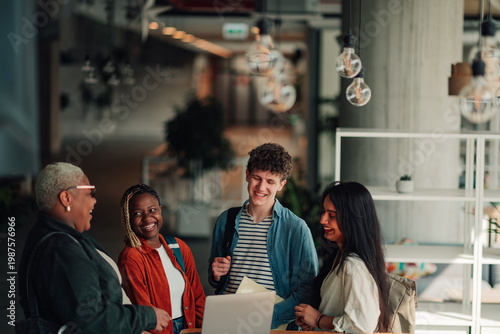 Diverse group of university students and professor collaborating and smiling during a discussion in modern campus lounge