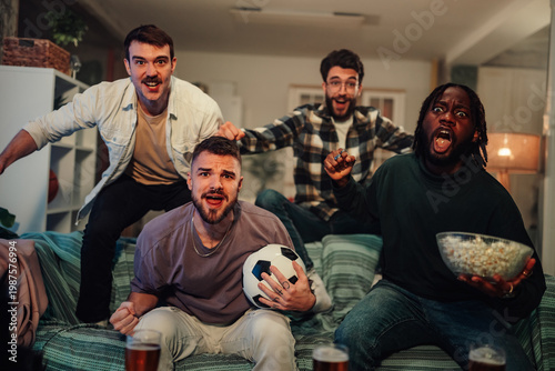 Foto Diverse friends cheering loudly while watching an exciting soccer game on televi