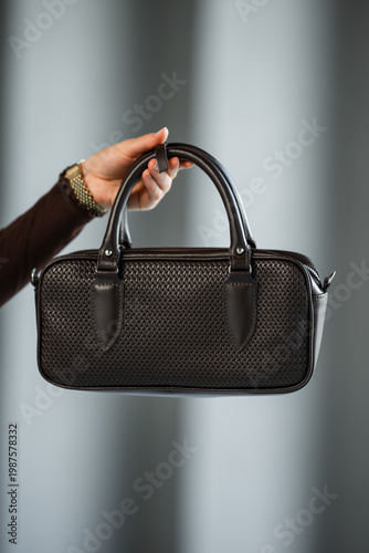 Wallpaper Mural Black Leather Purse Held By Hand, Neutral Grey Backdrop, Textured Grain, Polished Handles, Studio Lighting, Torontodigital.ca