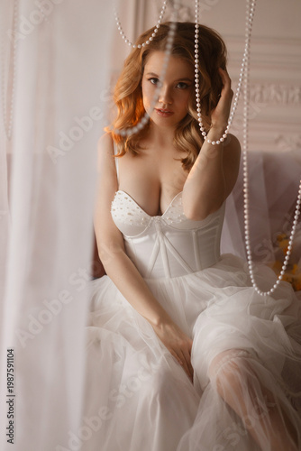 Woman Seated In Corset Among Pearls And Tulle, Direct Eye Contact With Confident Softness, Elegant Posture And Hand Gesture Create Regal Boudoir Narrative, Styling Suited For Bridal Boudoir,
