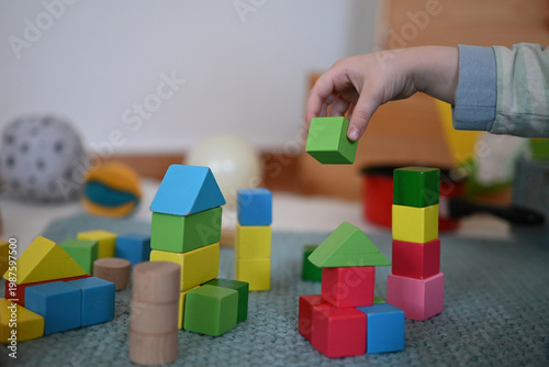 Close-up of a toddler playing with blocks and holding one block in the hand. 