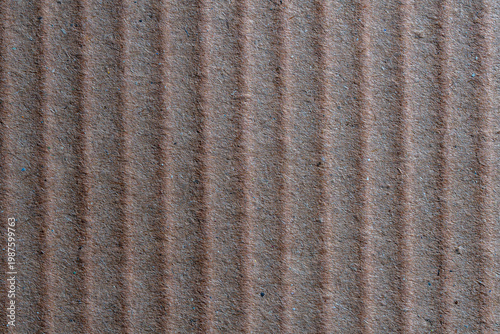 Brown corrugated cardboard texture background. Macro shot of brown corrugated cardboard with vertical ridges. Recycled paper texture for packaging shipping and eco friendly design concepts