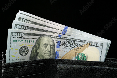 фотографія A black leather wallet filled with a stack of new hundred-dollar bills, showcasi