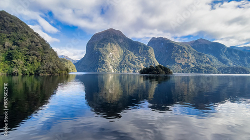 Photos Reflections of the towering mountains and cliffs at Doubtful Sound on a blue sky