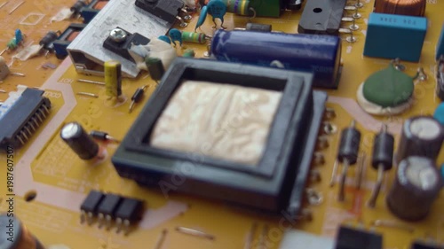 Macro footage of electronic parts on a circuit board including copper coils, capacitors, and microchips. High quality technical background for engineering, hardware, and repair concepts.