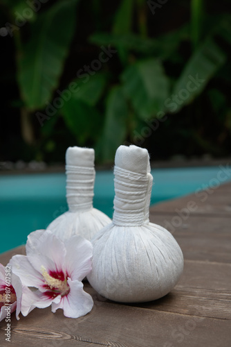 Set of  thai herbal heat bag for asian thai massage with flowers on wooden background front of the pool. Recreation and health care concept.  Selective focus.