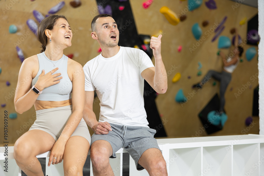 Fototapeta premium Young man and woman in sportswear chatting near climbing wall