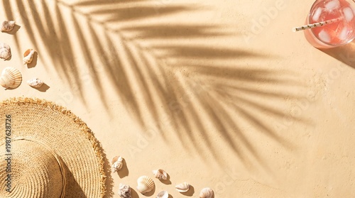 Straw hat with seashell and glass of beverage on sand. Tropical vacation background with palm leaf shadow. Summer holiday travel concept with copy space for design or promotional offer.